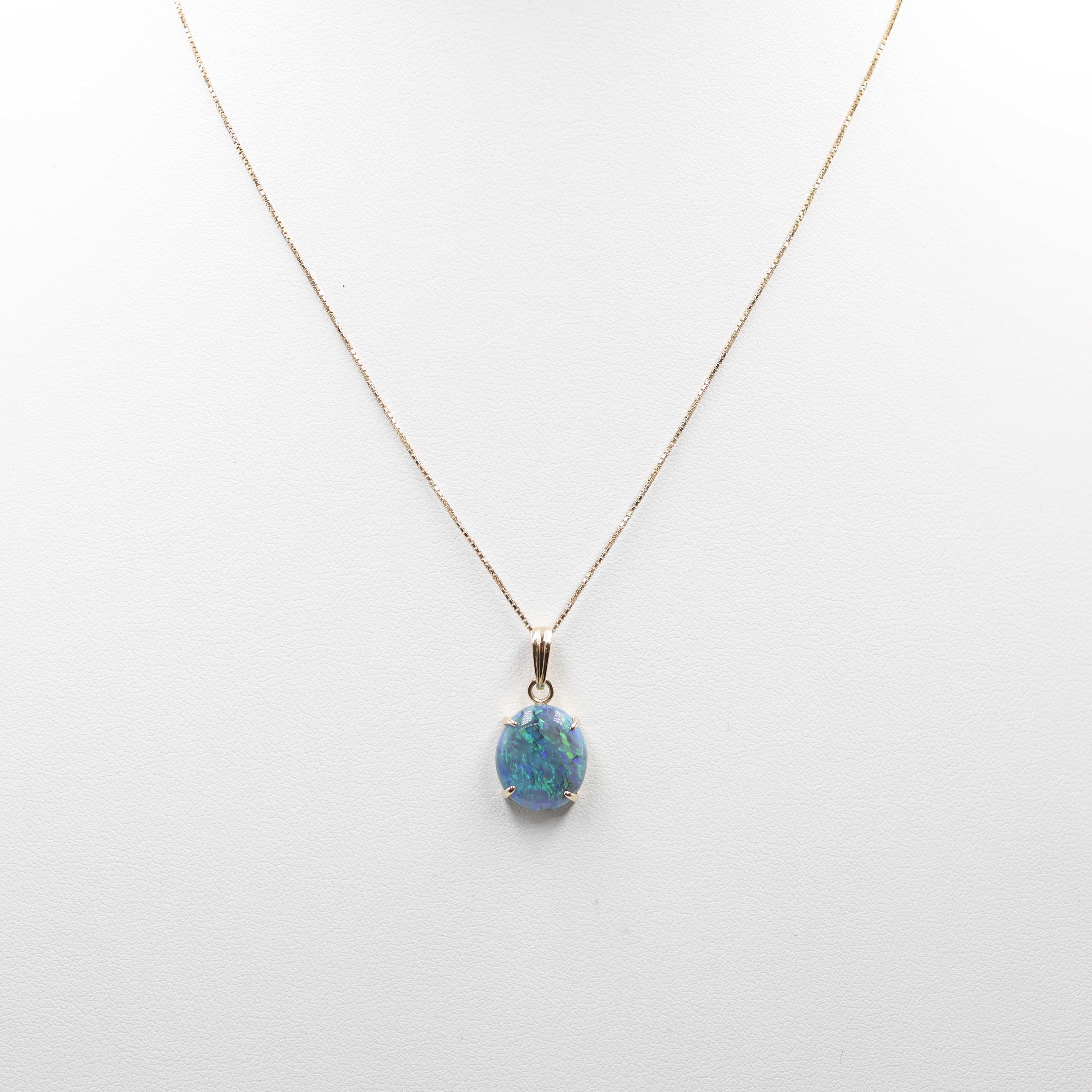 This is an elegant Opal Necklace featuring a striking oval-cut opal pendant suspended from a fine chain. The setting and chain are crafted from 18K Yellow Gold (YG). The key features include: